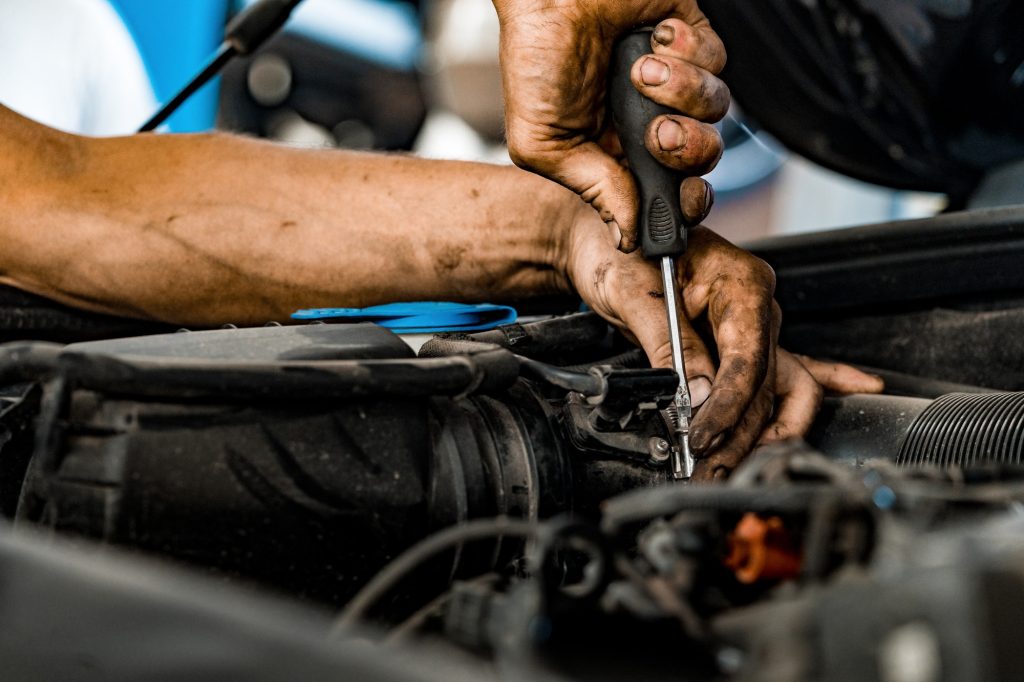Close up of auto mechanic repairing car engine in car service